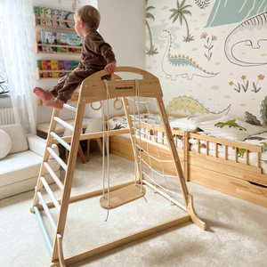 Parco giochi in legno al coperto con altalena, anelli da ginnastica e rete da arrampicata